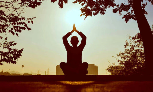 Persona meditando al atardecer en posición de loto, simbolizando bienestar y equilibrio natural que aportan los suplementos de Naturecan