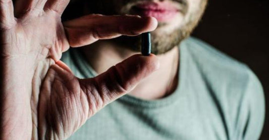 hombre sujetando una pastilla con dos dedos